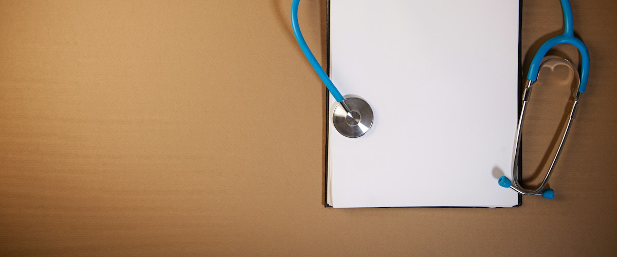 Clipboard with stethoscope on a brown background